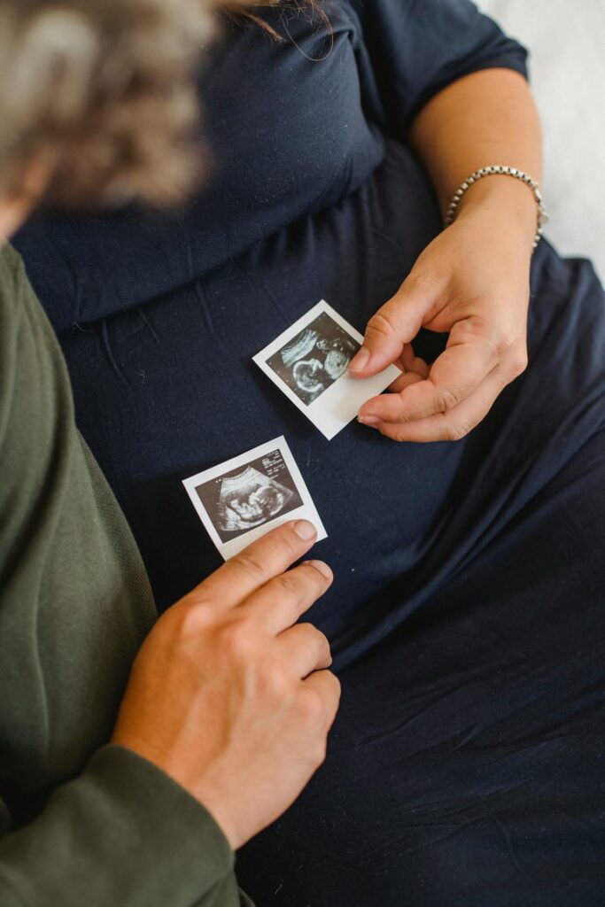 pierwszy trymestr ciąży: kobieta i mężczyzna kładą zdjęcia USG na brzuchu kobiety