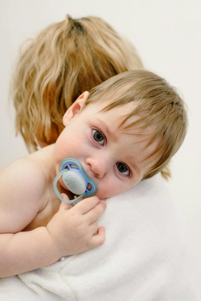 Odsmoczkowanie dziecka: dziecko ze smoczkiem przytulone do mamy