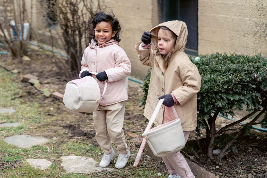 Dziewczynki z koszyczkami szukające jajek wielkanocnych na podwórku