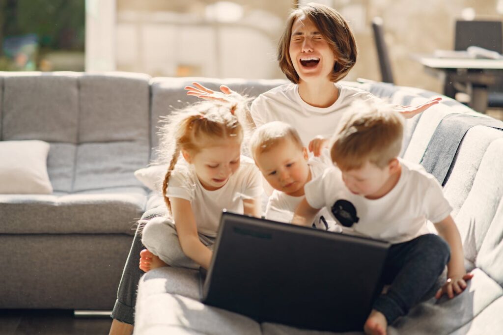 kobieta płacze z bezsilności. Przed nią na kanapie siedzi troje małych dzieci i bawi się laptopem.