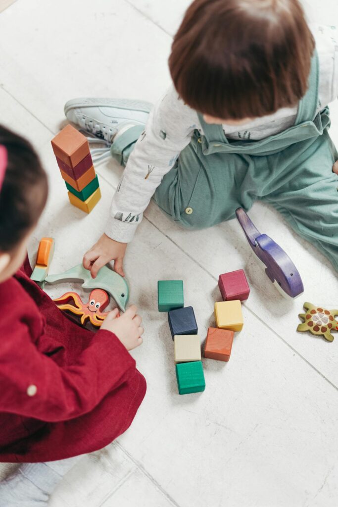 zabawki sensoryczne dla dzieci na podłodze i dwoje dzieci bawiące się nimi