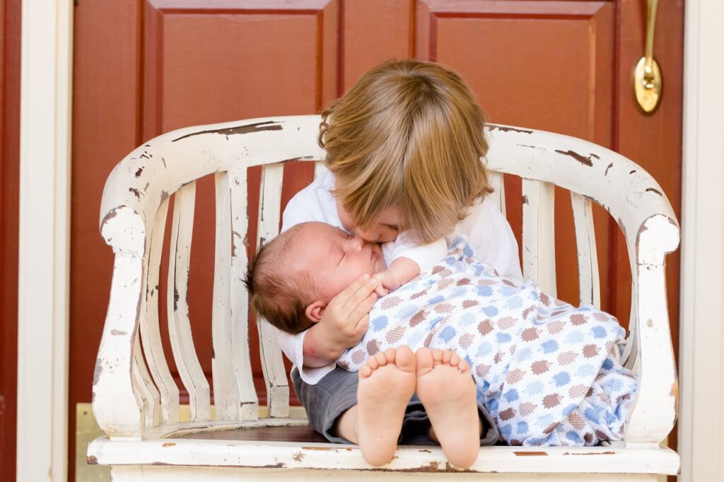 Chłopiec siedzi na ławce i przytula niemowlę