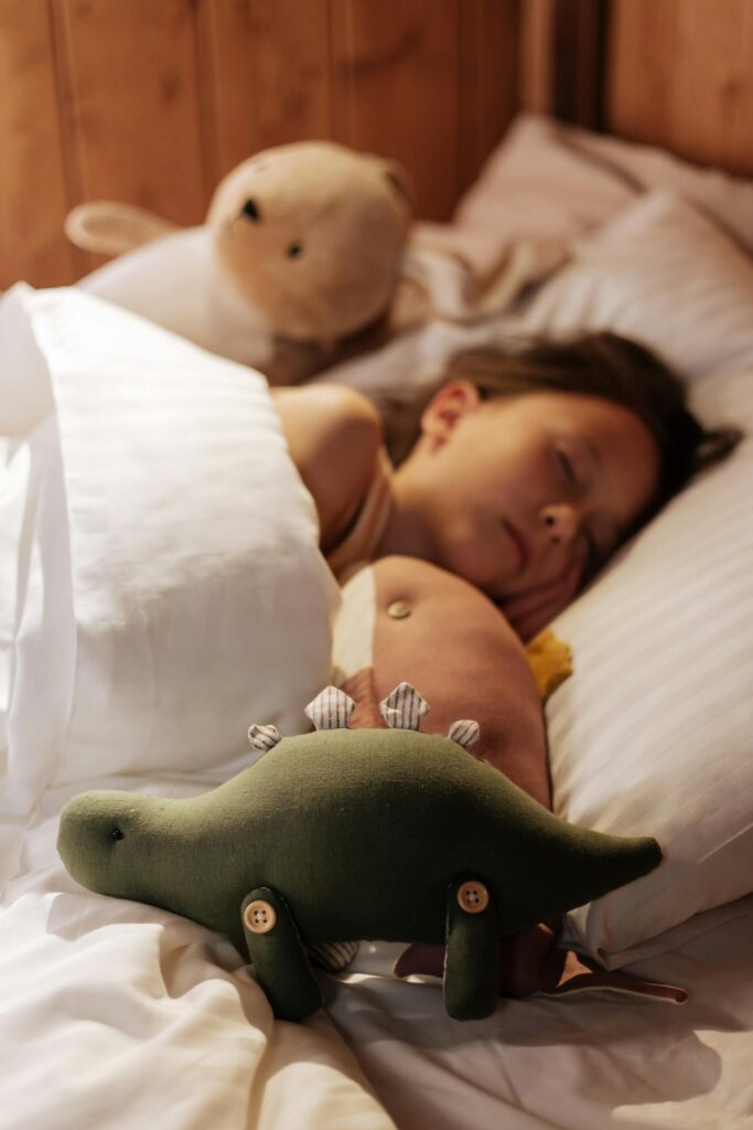 Czy dziecko powinno spać z rodzicami? Dziewczynka śpi w swoim łóżku w otoczeniu maskotek